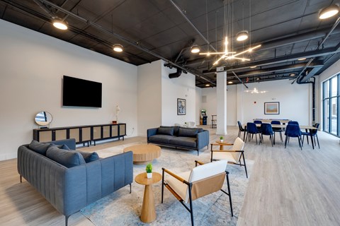 A modern living room with a grey sofa, a wooden coffee table, and a television on the wall.