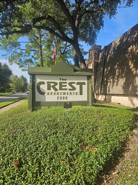 A sign for The Crest Apartments stands in front of a building.