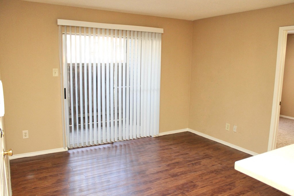 an empty living room with a sliding glass door and wood floors