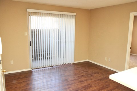 an empty living room with a sliding glass door and wood floors