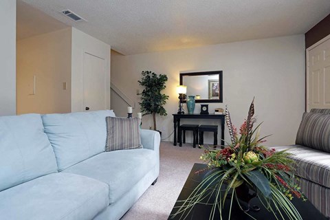 A living room with a light blue couch and a flower arrangement on the coffee table.