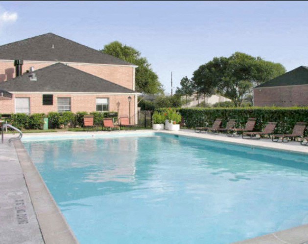 a swimming pool with chairs in front of a house