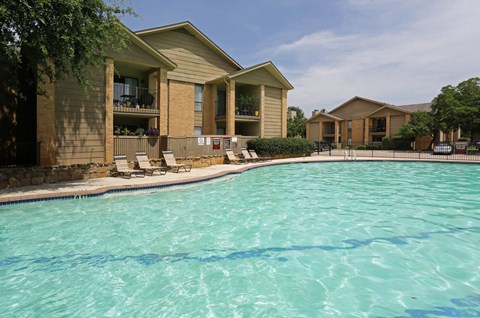 A swimming pool in front of a building with a sunny day.