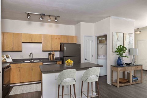 a kitchen with an island with two stools and a refrigerator