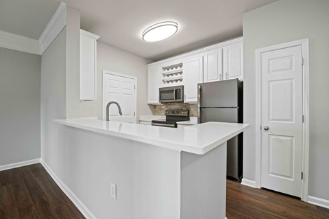 A kitchen with white cabinets and a white countertop.