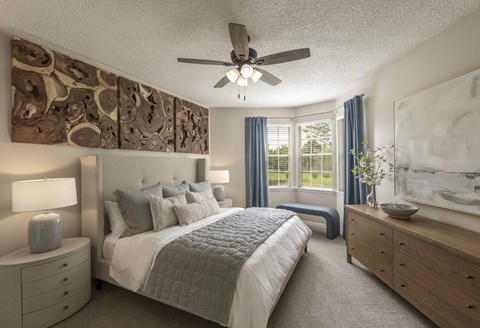 A bedroom with a bed, dresser, and ceiling fan.
