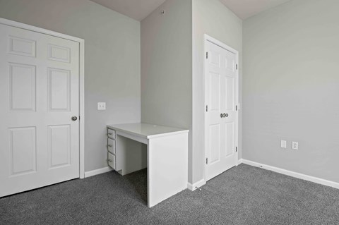 A white desk in a room with two doors.