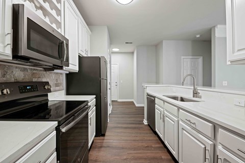 A kitchen with black and white appliances and wooden floors.