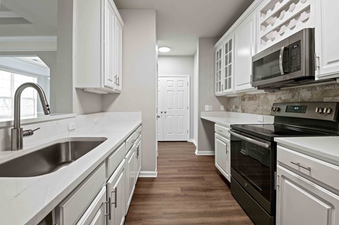 A kitchen with white cabinets and a black oven.