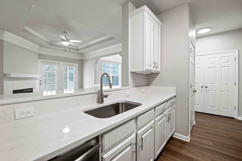 A modern kitchen with white cabinets and a marble countertop.
