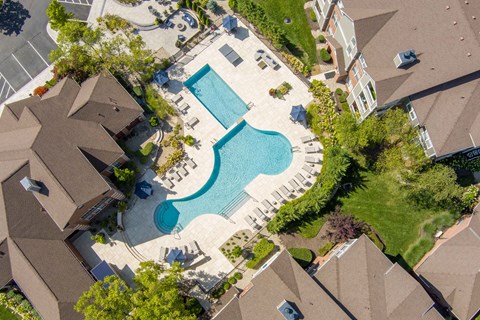 A swimming pool surrounded by a grassy area and a few trees.
