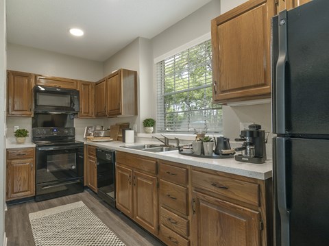 A kitchen with wooden cabinets and black appliances.