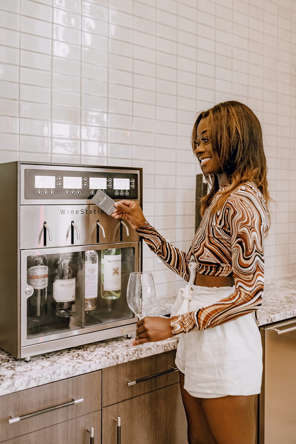 a woman standing in front of a wine dispenser in a kitchen