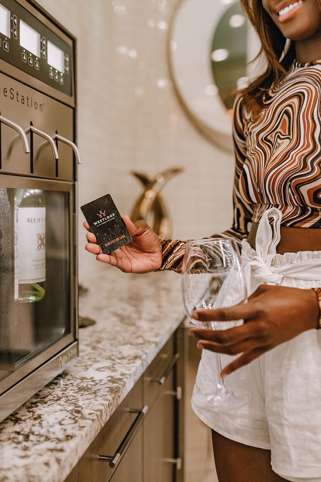 a woman holding a bottle of wine in front of a microwave and a wine glass