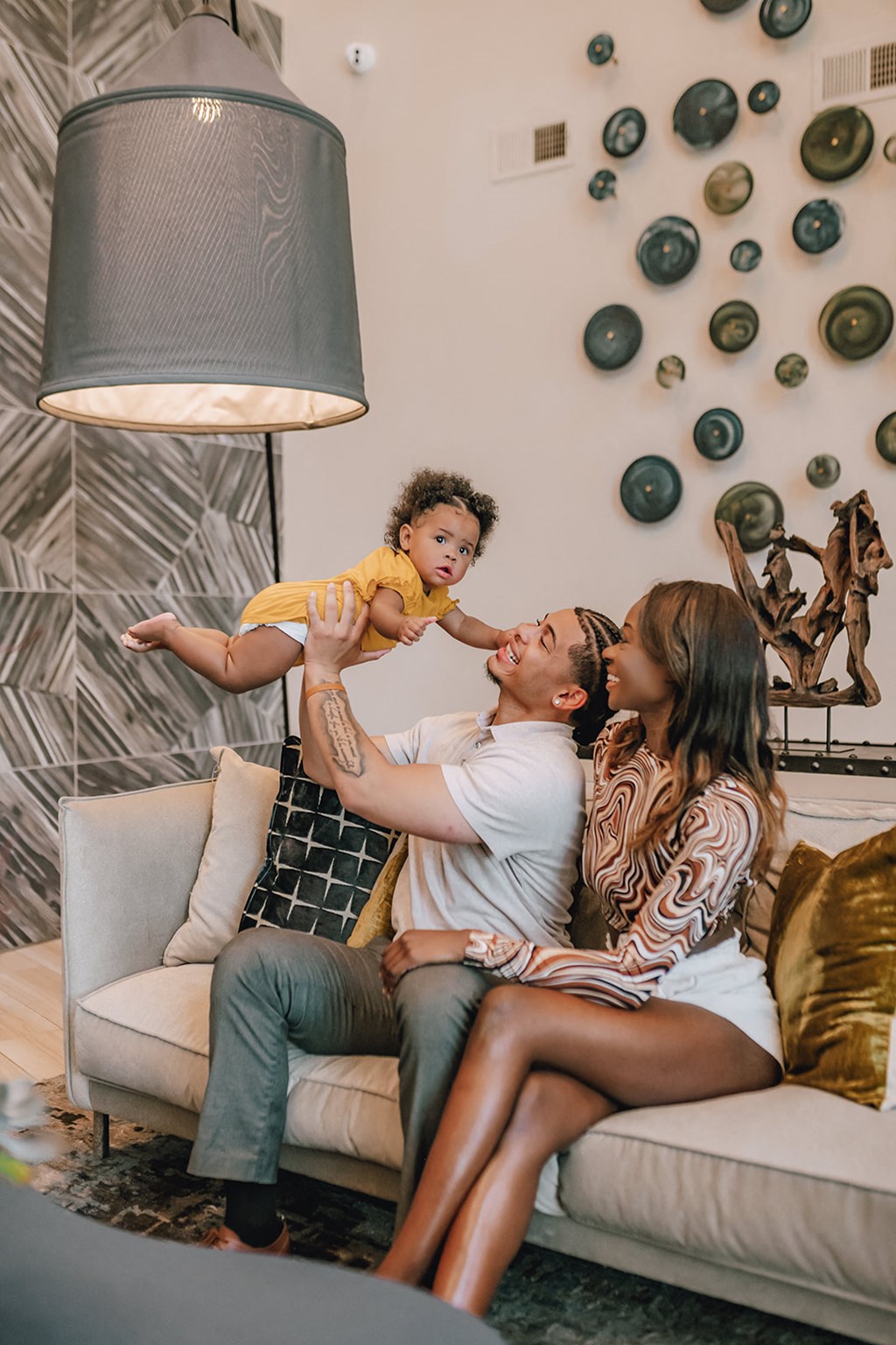 a mother and father playing with their child on the couch
