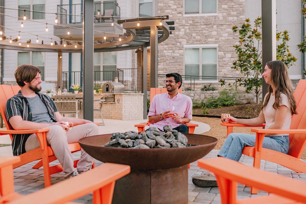 a group of people sitting around a fire pit on a patio