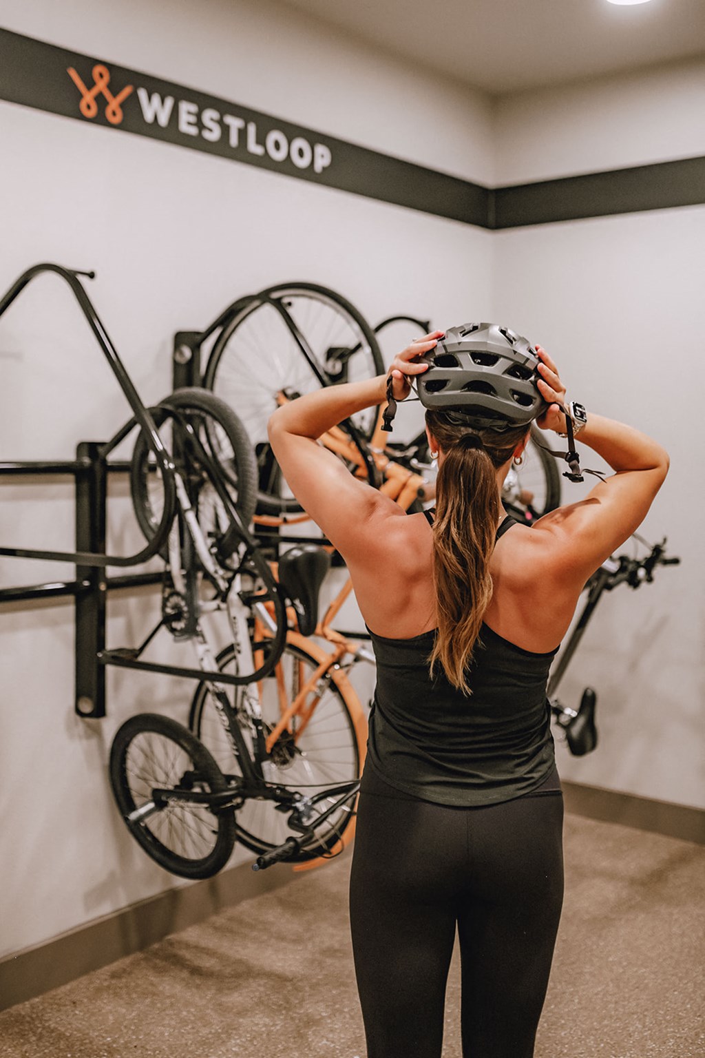 a woman holding a bike helmet on her head in front of a rack of bikes