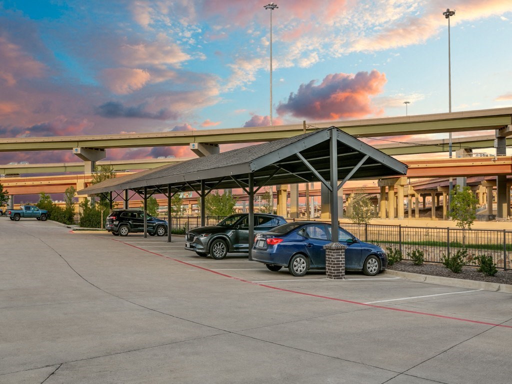 a parking lot with cars under an overhang at a gas station