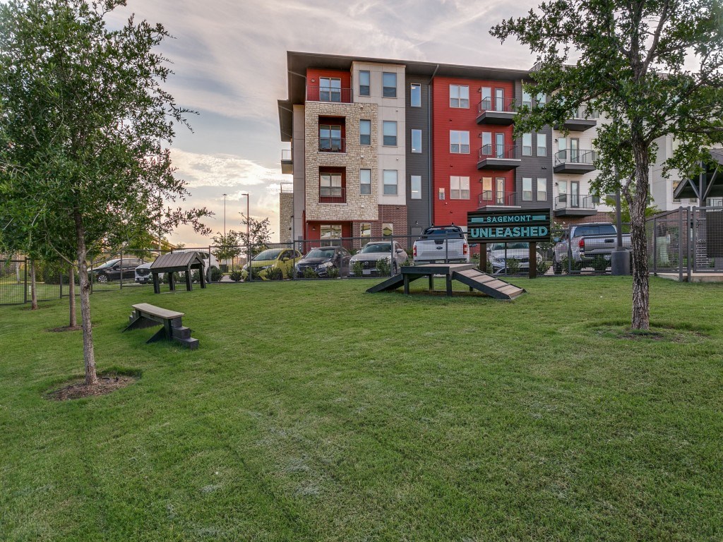 a green park with benches and an apartment building in the background