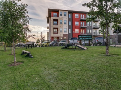 a green park with benches and an apartment building in the background