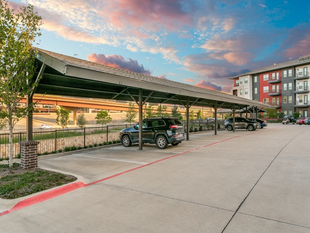 a covered parking lot with cars parked in front of a building