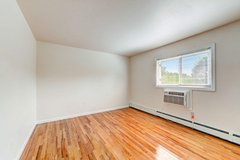 the living room of an empty house with wood floors and a window
