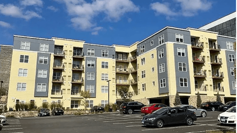 A parking lot in front of a building with cars parked.