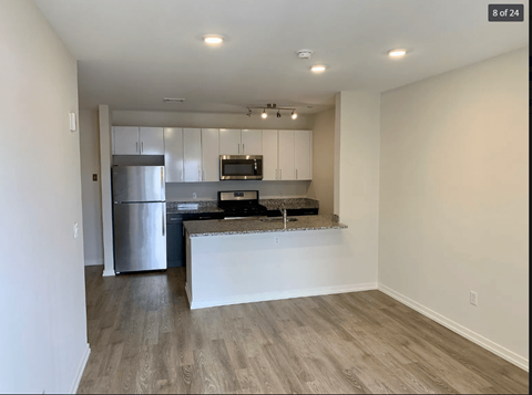 A kitchen with a refrigerator, microwave, and a countertop.