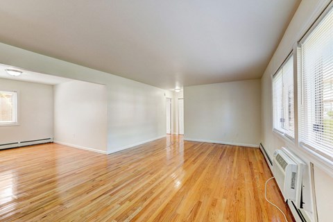 an empty living room with wood floors and large windows
