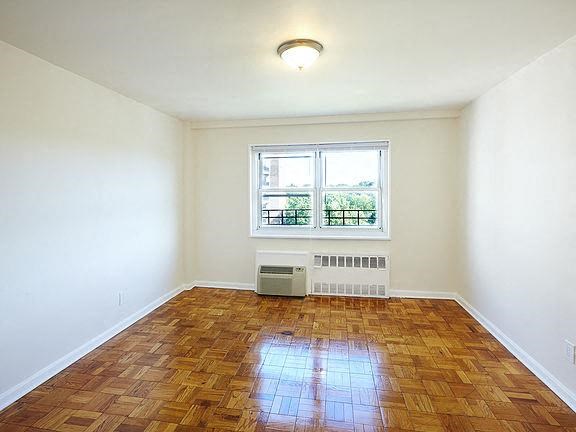 an empty room with a window and wooden floors