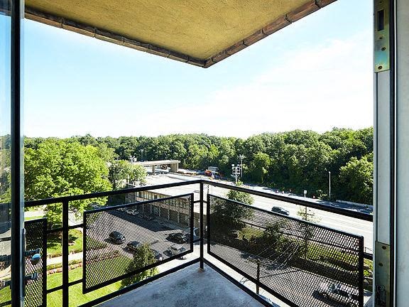 a balcony with a view of a parking lot and trees