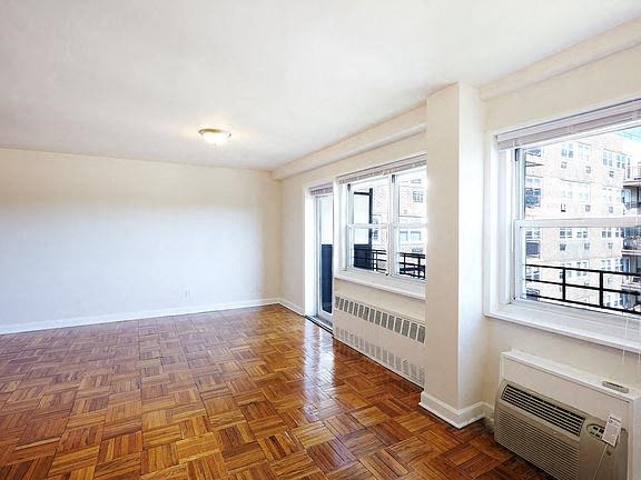 an empty living room with a wood floor and two windows