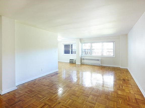 an empty living room with a wood floor and a window