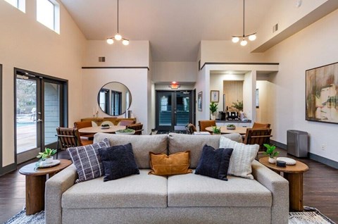 A living room with a grey couch and a round mirror on the wall.