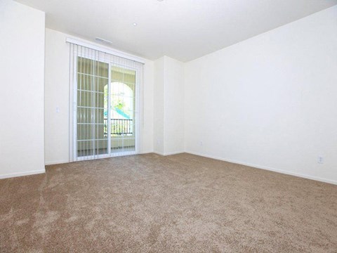 an empty living room with a door to a balcony
