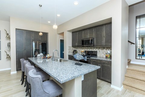 A modern kitchen with a granite countertop and grey chairs.