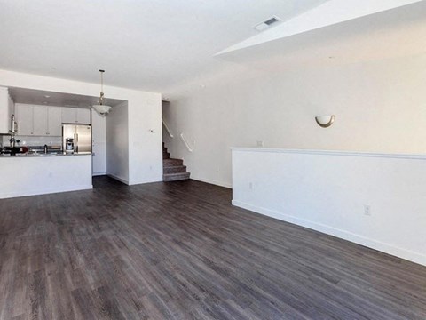 the living room and kitchen of an empty house with wood flooring
