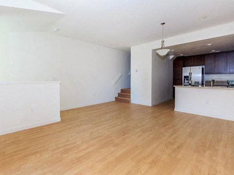 an empty living room and kitchen with a wooden floor