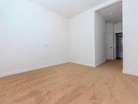 an empty living room with a carpeted floor and white walls
