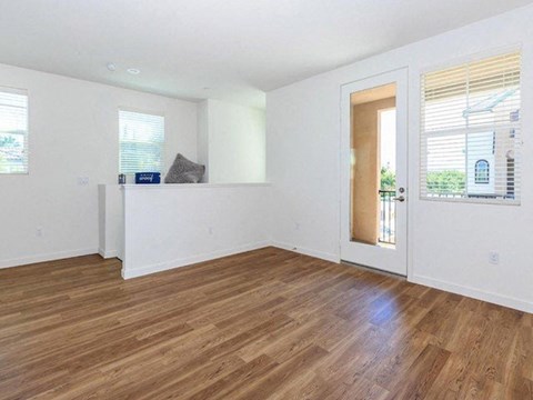 an empty living room with wood floors and a door to a balcony