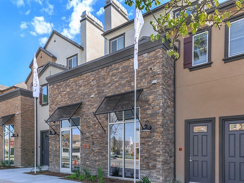 a brick building with windows and a flag on the sidewalk