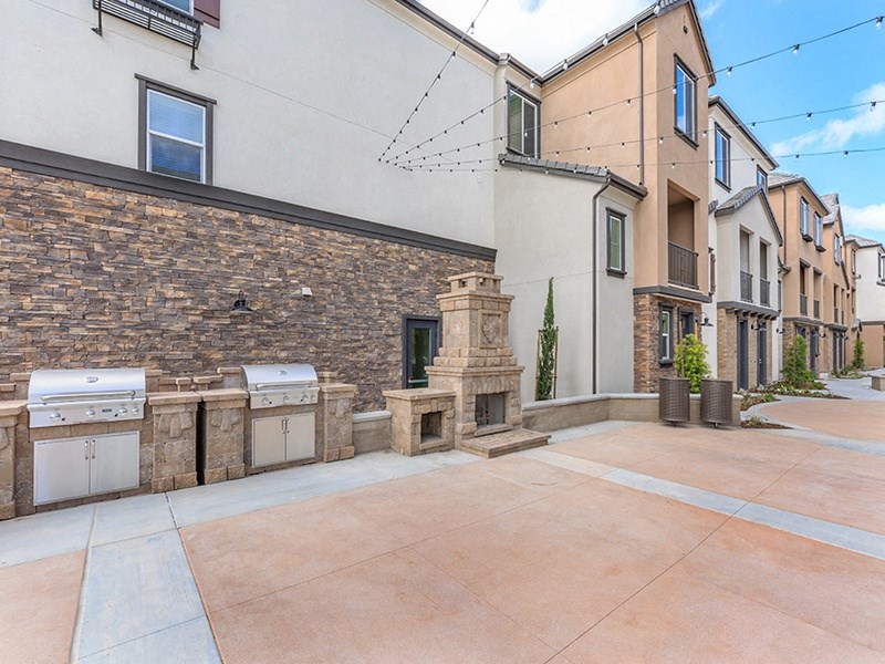 the backyard of a house with two barbecue pits and a stone pillar