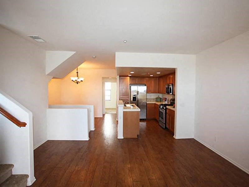 an empty living room and kitchen with a wood floor