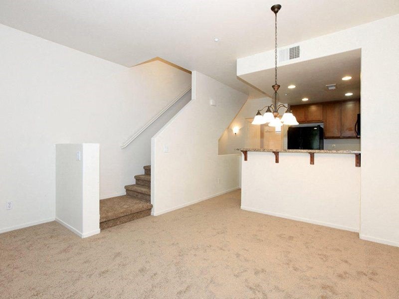 an empty living room with a kitchen and stairs