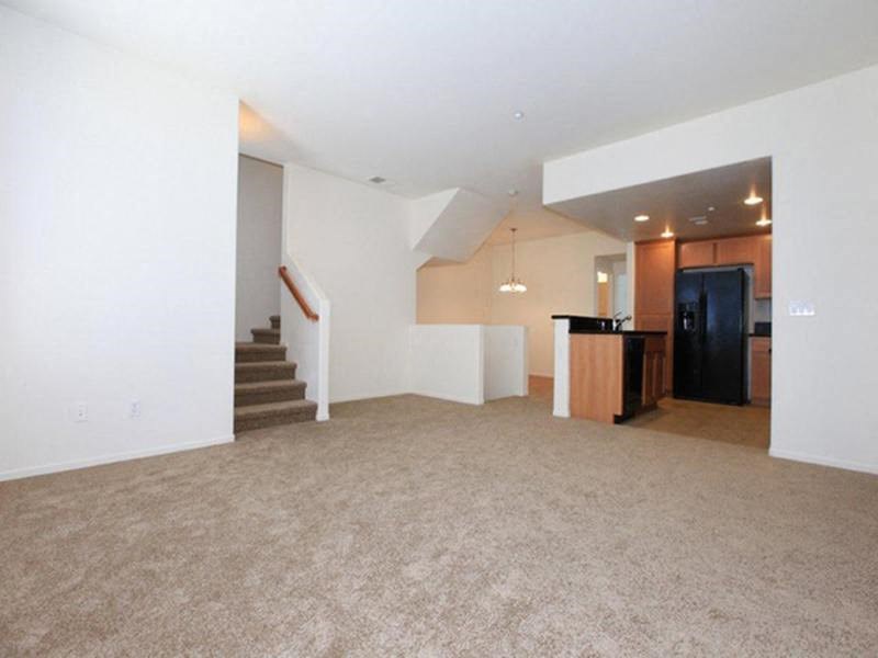 an empty living room with a kitchen and a staircase