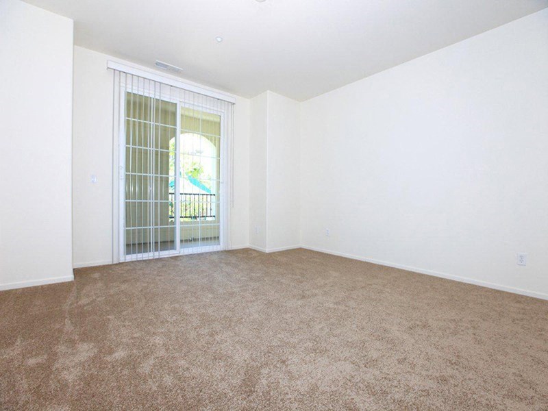 an empty living room with a sliding glass door to a balcony