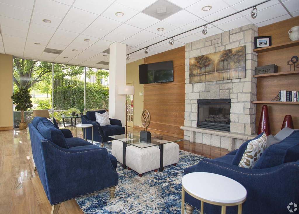 a living room with blue furniture and a stone fireplace at Vista Condominiums, Kansas City, KS 66103