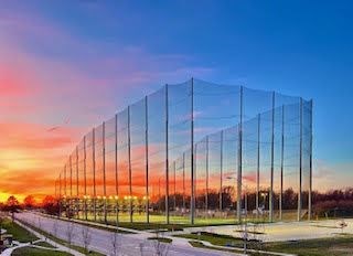 A long, tall, transparent fence stretches across a grassy field at Woodstone at Metro North Crossing Apartments, Kansas City, 64155