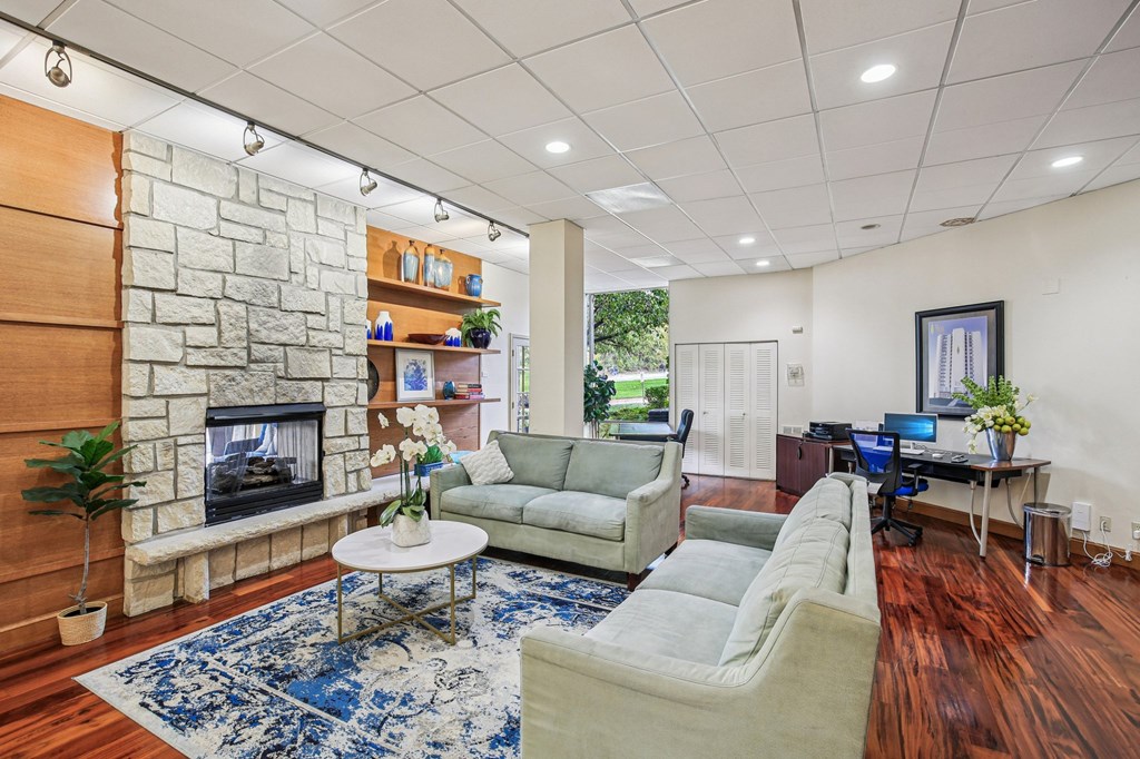 A living room with a stone fireplace and a blue rug.