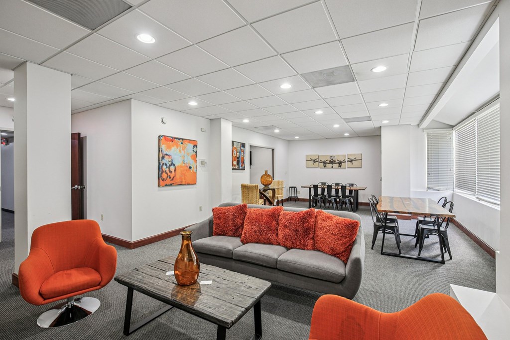A modern living room with a grey couch, orange chairs, and a wooden coffee table.